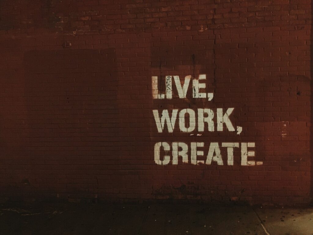 A brick wall with "live, work, create" painted on it
