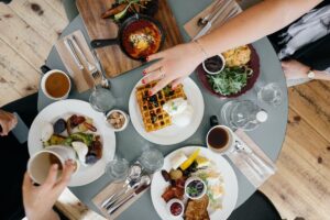 A picture from above featuring breakfast plates (like waffles, eggs, and potatoes) at a dining restaurant.